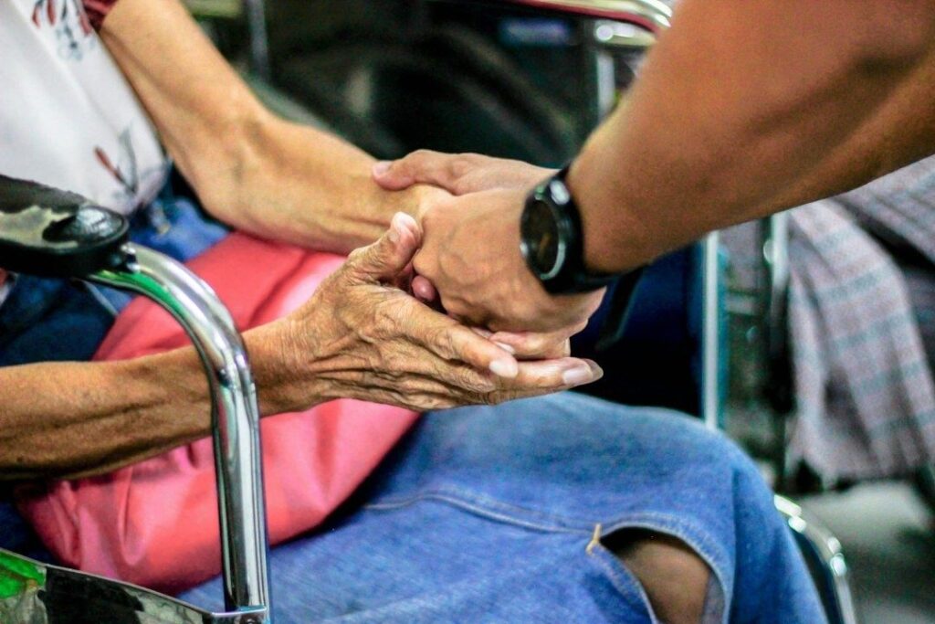 Oudere persoon krijgt steunende hand van een andere volwassene